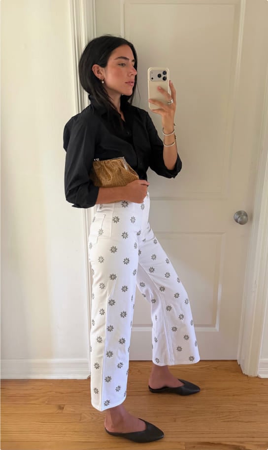 Ceci in a black blouse and white floral-print pants