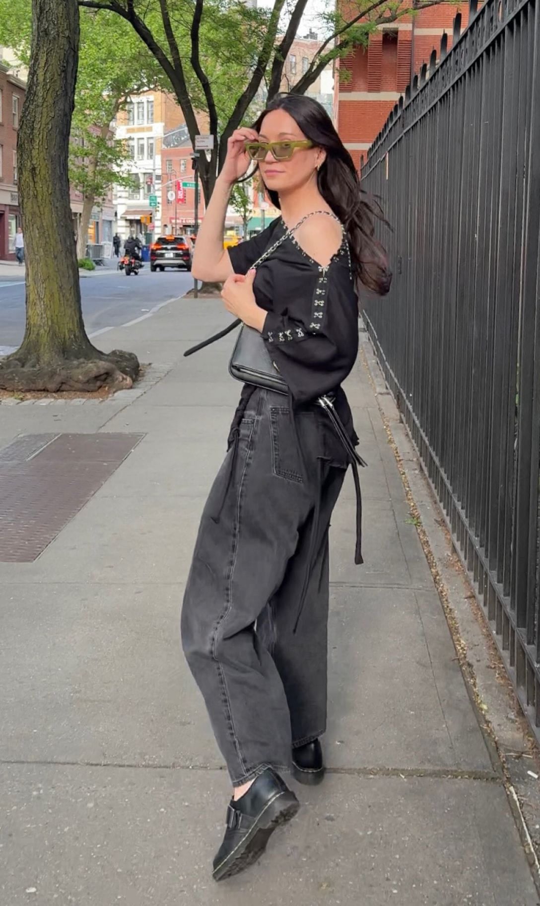 Aleksandra wearing a black off-the-shoulder top and wide-leg jeans