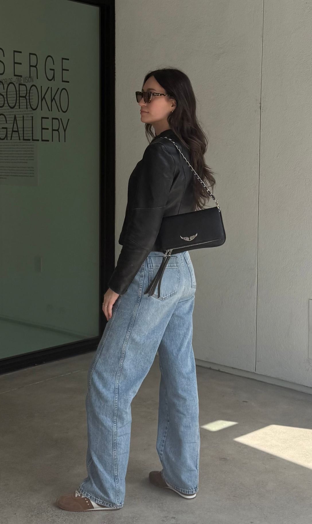 Aleksandra wearing a black leather jacket and wide-leg jeans